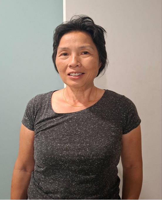 A close protrait of a middle-aged woman wearing a sleeveless shirt.