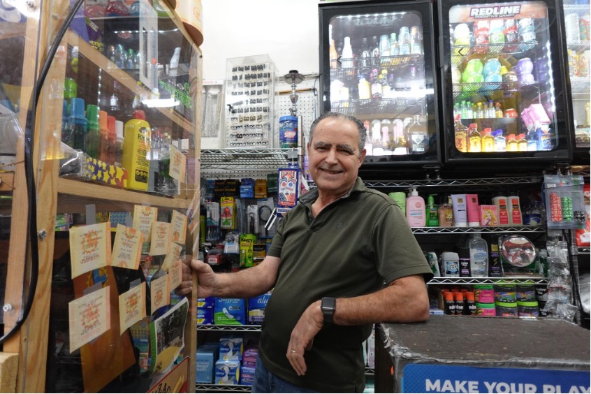 A middle-aged man stand behind the counter of his retail store