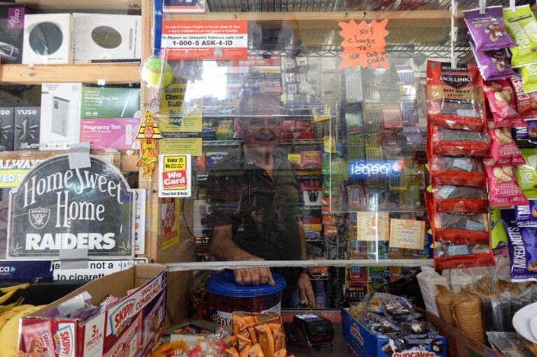 A middle-aged man stand behind the glass covered counter of his retail store
