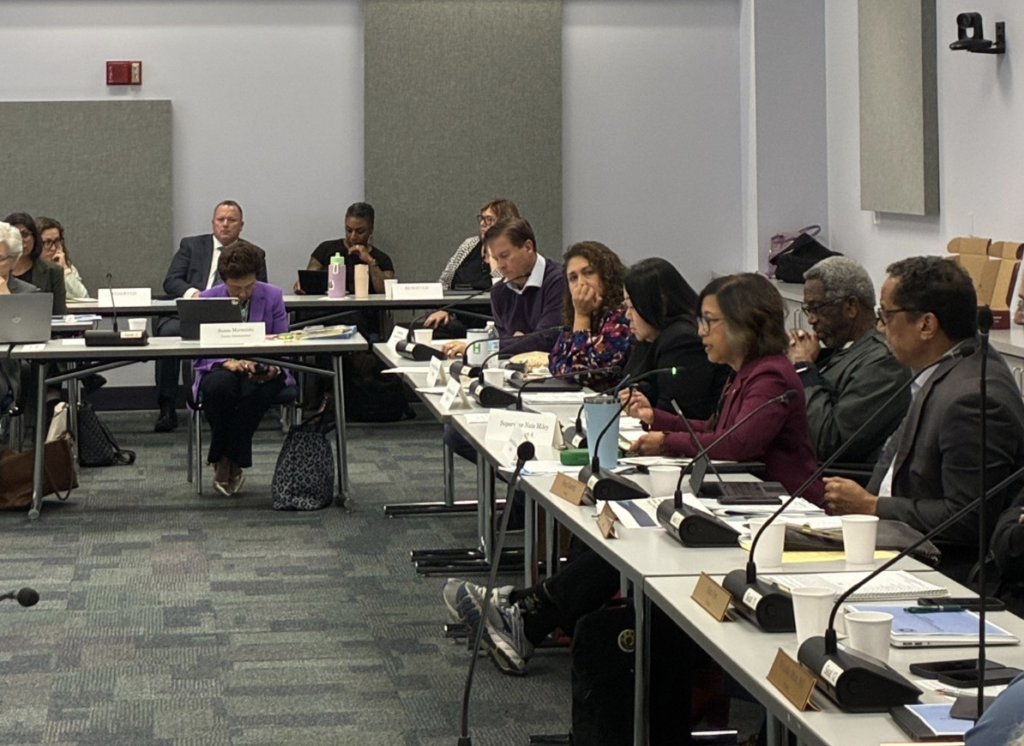 A group of people having a meeting in a big conference room.