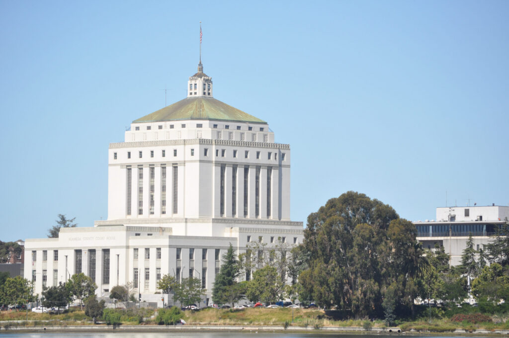 René C. Davidson Courthouse Across From Lake Merritt, a white columned building with a cupola at the top and a flag protruding from it.